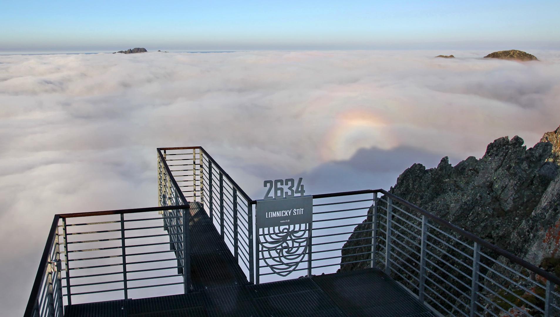 A glass-sided observation deck at dawn above a sea of cloud, with the number 2634 etched into the glass.